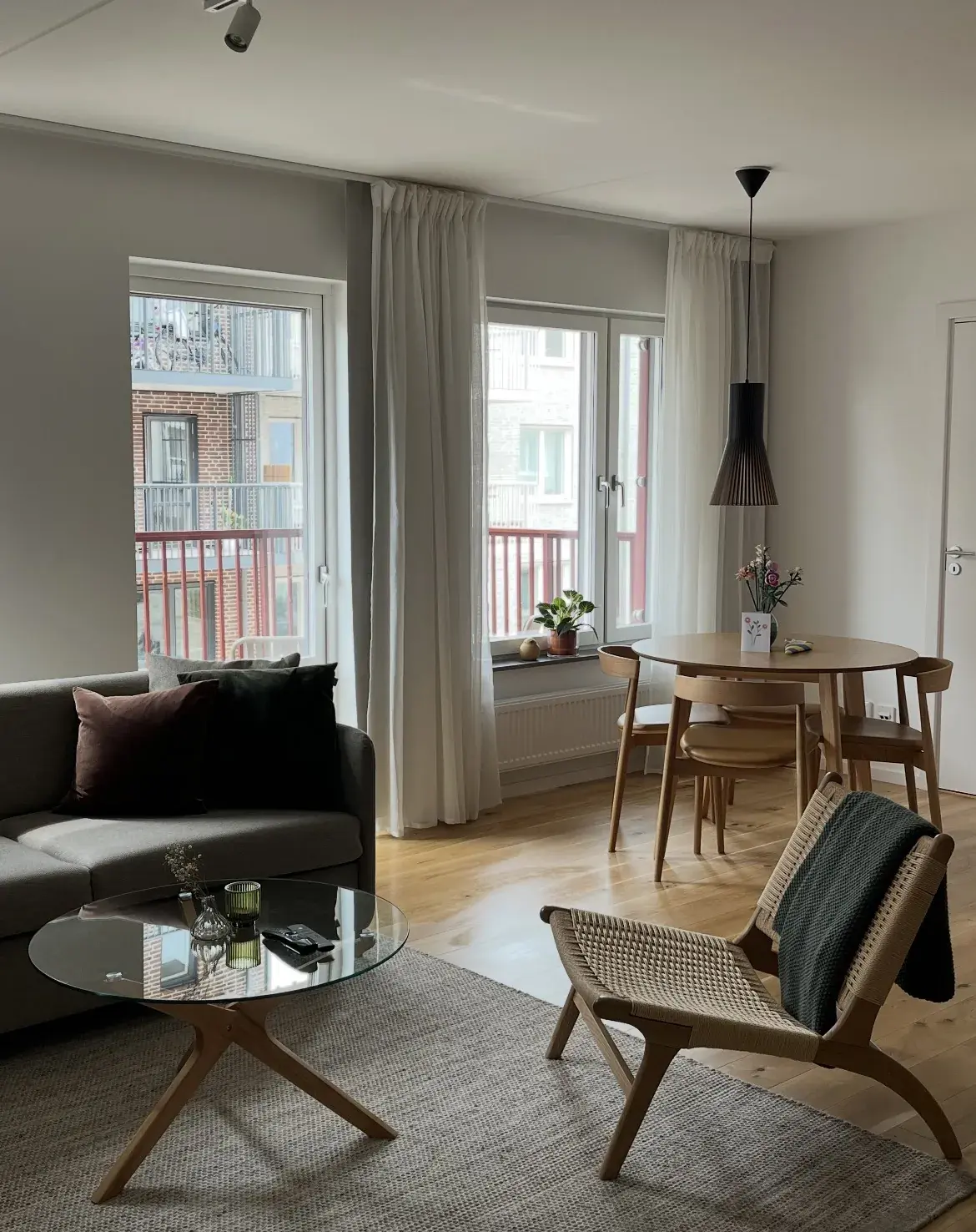 Ljust och städat lägenhetsvardagsrum med matplats och balkong, redo för gäster